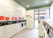 Thumbnail 31 of 49 - A row of washing machines are lined up in a laundromat.