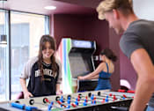 Thumbnail 6 of 49 - A man and a woman are playing a game of foosball.