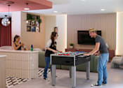 Thumbnail 3 of 49 - A man and two women are playing a game of foosball in a modern room.