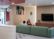 Thumbnail 27 of 49 - Two people sitting on a green couch in a living room.