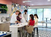 Thumbnail 1 of 49 - A group of people are gathered around a table in a kitchen.