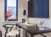 Thumbnail 11 of 37 - a desk in a room with a large window and a table with a chair