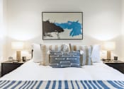 Thumbnail 12 of 37 - a bedroom with a bed with pillows and a painting on the wall