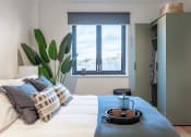 Thumbnail 25 of 37 - a bedroom with a bed with pillows and a window and a plant