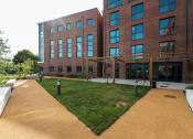 Thumbnail 33 of 39 - a large brick building with a grassy area in front of it