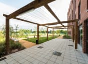 Thumbnail 34 of 39 - a pergola over a walkway in front of a brick building