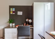 Thumbnail 27 of 39 - a small desk with a chair in front of a white fridge