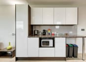 Thumbnail 14 of 39 - a small kitchen with white cabinets and a granite countertop