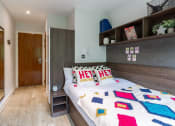 Thumbnail 19 of 39 - a bedroom with a bed with a colourful quilt on it