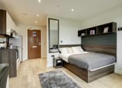 Thumbnail 22 of 39 - a bedroom with a bed and a kitchen