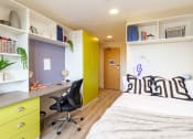 Thumbnail 18 of 50 - a bedroom with a bed and a desk with a chair