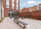 Thumbnail 47 of 50 - a courtyard with benches and picnic tables in front of a brick building