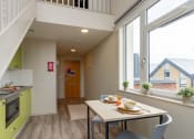 Thumbnail 39 of 50 - a dining area with a table and chairs and a kitchen with green cabinets and a large window