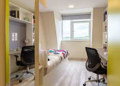 Thumbnail 21 of 50 - a bedroom with a bed and two desks