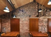 Thumbnail 14 of 49 - a brick walled room with wooden tables and chairs