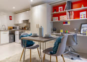 Thumbnail 38 of 49 - a dining area with a small table and two chairs and a kitchen in the background