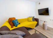 Thumbnail 19 of 49 - a living room with white walls and a yellow couch