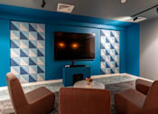 Thumbnail 13 of 51 - Cinema room television and seating nearby. The TV is wall-mounted against a blue patterned wall.
