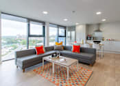 Thumbnail 21 of 51 - Shared flat sofa and coffee table, with large windows with a view of greenery outside.