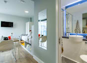 Thumbnail 28 of 51 - Image of bedroom from the bathroom, showing the large bathroom mirror, a wall-mounted mirror and bed.