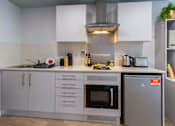 Thumbnail 29 of 51 - A White studio kitchen space with an oven, fridge, hobs, extractor fan, cupboards and drawers.