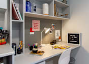 Thumbnail 31 of 51 - Close up of white desk, with a small lamp and a chair.