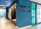 Thumbnail 38 of 51 - Positive wall-art stating 'Make It Happen' against a blue wall, near to the reception.