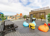 Thumbnail 44 of 51 - A modern roof-top patio with bean bags and a wooden bench.