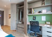 Thumbnail 8 of 48 - A room with a desk and a chair with a green wall behind it.