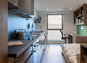 Thumbnail 11 of 48 - A kitchen with a black counter top and a window with blinds.