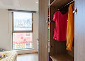 Thumbnail 30 of 48 - A red shirt is hanging on a wooden door.