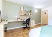 Thumbnail 34 of 35 - A room with a desk, chair, and bed.