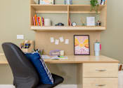 Thumbnail 30 of 35 - A home office with a desk, chair, and shelf with various items.