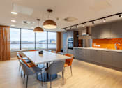 Thumbnail 6 of 36 - A modern kitchen with a dining table and chairs.