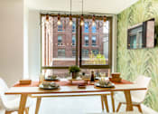 Thumbnail 7 of 21 - A dining table with chairs and a potted plant is set for a meal.