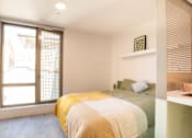 Thumbnail 10 of 21 - A bedroom with a bed covered in a yellow and white blanket.