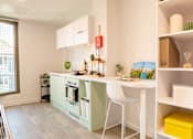 Thumbnail 9 of 21 - A kitchen with a white table and chairs and a green cabinet.