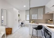 Thumbnail 12 of 21 - A modern kitchen with a white countertop and a black bar stool.