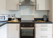 Thumbnail 32 of 33 - a kitchen with white cabinets and a black counter top and a oven and a microwave