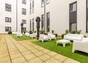 Thumbnail 27 of 33 - a courtyard with lawn chairs and tables in front of a building