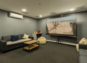Thumbnail 19 of 33 - a living room with a projector screen and couches