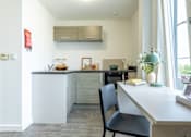 Thumbnail 9 of 59 - A kitchen with a white counter and a black chair.