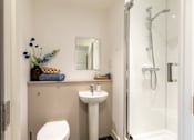 Thumbnail 26 of 59 - A small bathroom with a toilet, sink, and shower.