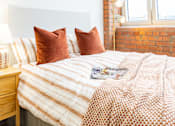 Thumbnail 12 of 59 - A bed with a white headboard and a striped comforter with two pillows on it.