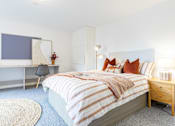 Thumbnail 1 of 59 - A bedroom with a bed, desk, chair, and a rug.