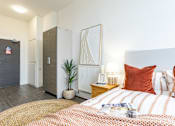 Thumbnail 2 of 59 - A bedroom with a bed, nightstand, and a plant.