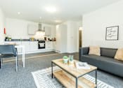 Thumbnail 18 of 59 - A modern living room with a grey couch and a wooden coffee table.