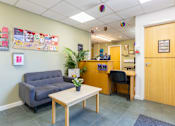 Thumbnail 2 of 35 - A waiting room with a couch, chair, and a table.