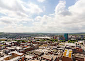 Thumbnail 3 of 51 - A cityscape with buildings and a cloudy sky.