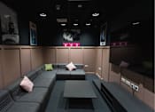 Thumbnail 5 of 23 - A room with a grey couch and a black table.